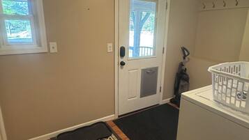 A laundry area with a washing machine, a door with a window, and a doormat.