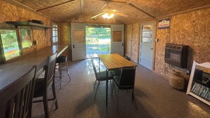 A rustic interior with a wooden ceiling, a bar area, a dining table with chairs, and a gas stove. - Ride, Relax & Recharge at Sleepy Hollow Hideaway (Roscommon)