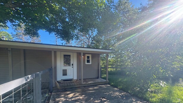 A single-story building with a front door, a small porch, and a gravel driveway. - Ride, Relax & Recharge at Sleepy Hollow Hideaway (Roscommon)