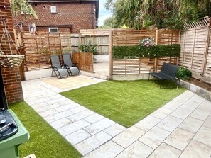 Ein Garten mit Terrasse, Holzzaun und Rasenfläche.