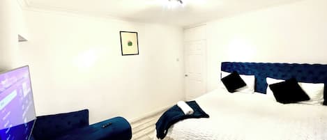 A hotel room with a bed, a desk, a chair, and a ceiling fan.