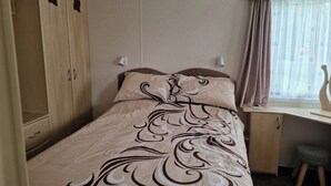 A bedroom with a bed, a desk, and a wardrobe. - Caravan Sleeps 6 with Parking (Great Yarmouth)