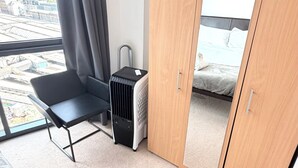 Hotelkamer met een bed, een stoel, een koffer, een verwarming en een kledingkast.