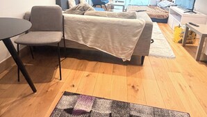 Een moderne woonkamer met een bank, een fauteuil, een bijzettafeltje en een televisie.