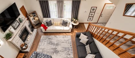 A modern living room with a fireplace, a sofa set, a coffee table, and a staircase.