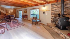 Un interior de madera con chimenea, mobiliario de cuero y una escalera.
