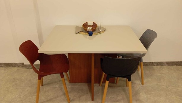 Una mesa de comedor con cuatro sillas, una cesta y un objeto azul sobre la mesa.