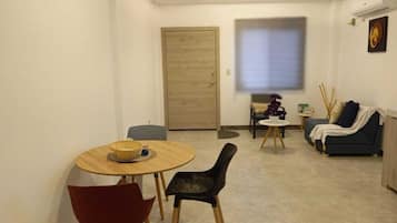 Un espace de vie compact comprenant un coin repas, un canapé et une petite table agrémentée d’un objet décoratif.