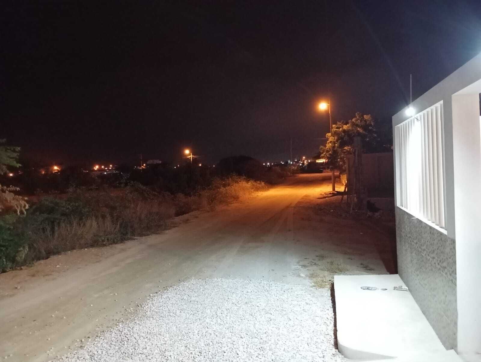A nighttime view of a rural road with streetlights and a building on the right.