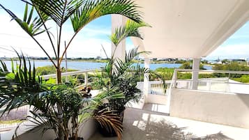 Un balcon agrémenté de plantes en pot, une vue sur la mer et une balustrade blanche.