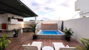 Terraza en la azotea con piscina, zona de estar y plantas en macetas.