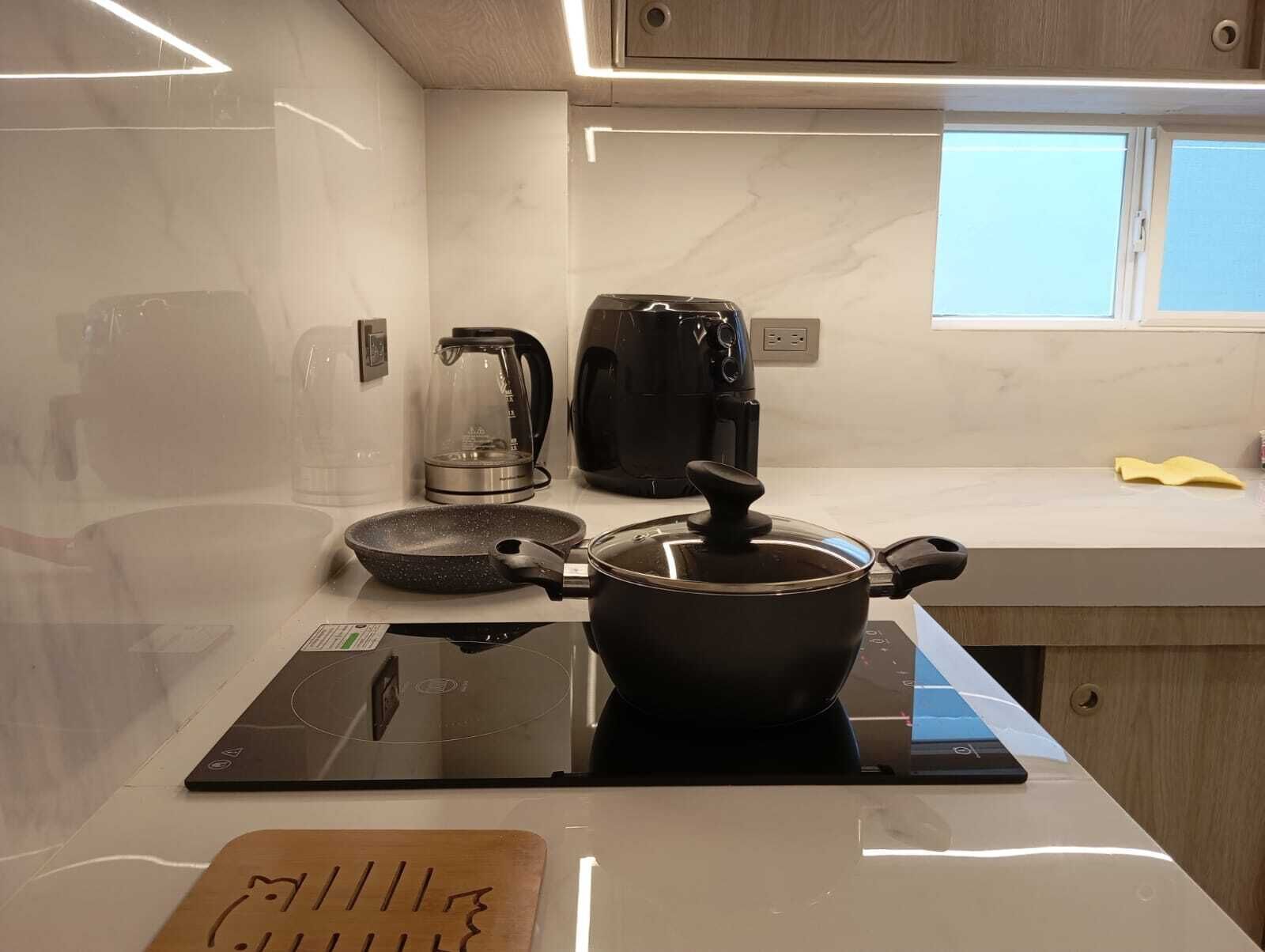 Een moderne keuken met een ingebouwde kookplaat, een koffiezetapparaat en een waterkoker op het aanrecht.
