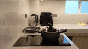 Een moderne keuken met een ingebouwde kookplaat, een koffiezetapparaat en een waterkoker op het aanrecht.