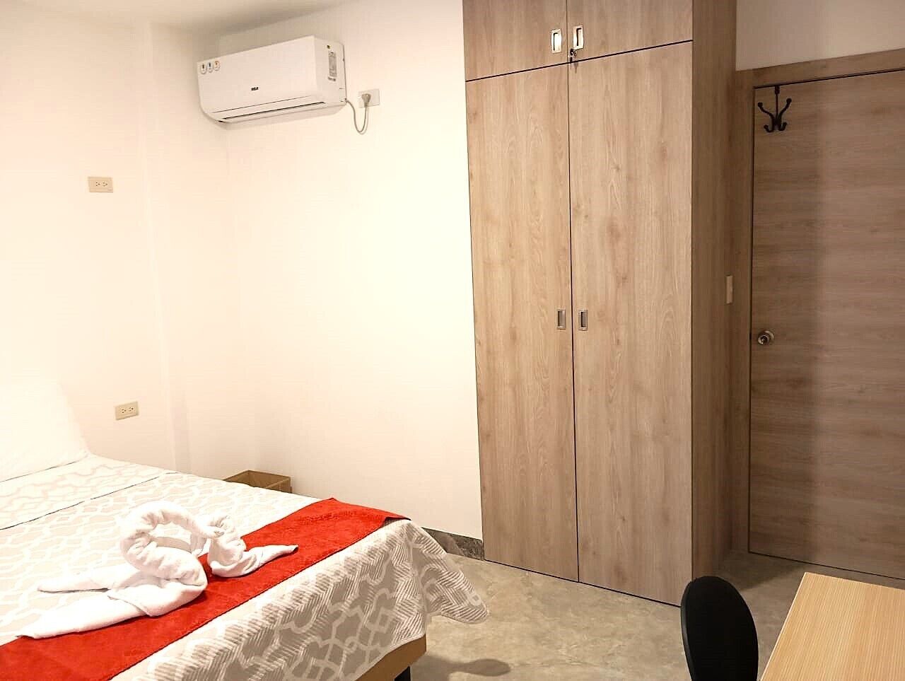 Quarto de hotel com uma cama, um guarda-roupa e um ar condicionado.