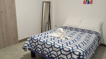A bedroom with a bed, a mirror, and two wall art pieces.