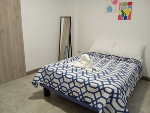 A bedroom with a bed, a mirror, and two wall art pieces.