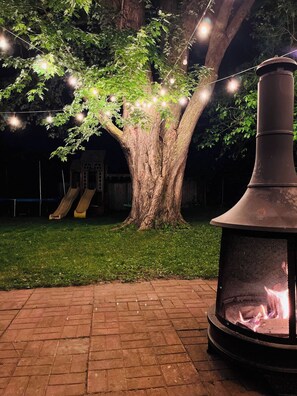 A tree with string lights, a slide, and a fire pit. - Rockway Retreat - Spacious Home & Backyard Oasis (Kitchener)