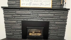 Une cheminée avec une façade en pierre et une citation encadrée au-dessus.