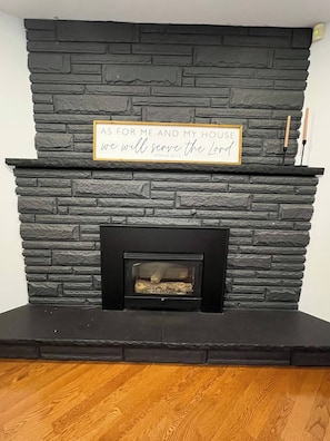 A fireplace with a stone facade and a framed quote above it.