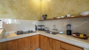 A kitchen with a gas stove, a sink, a blender, and wooden cabinets. - Sona Villa Bali (Badung)