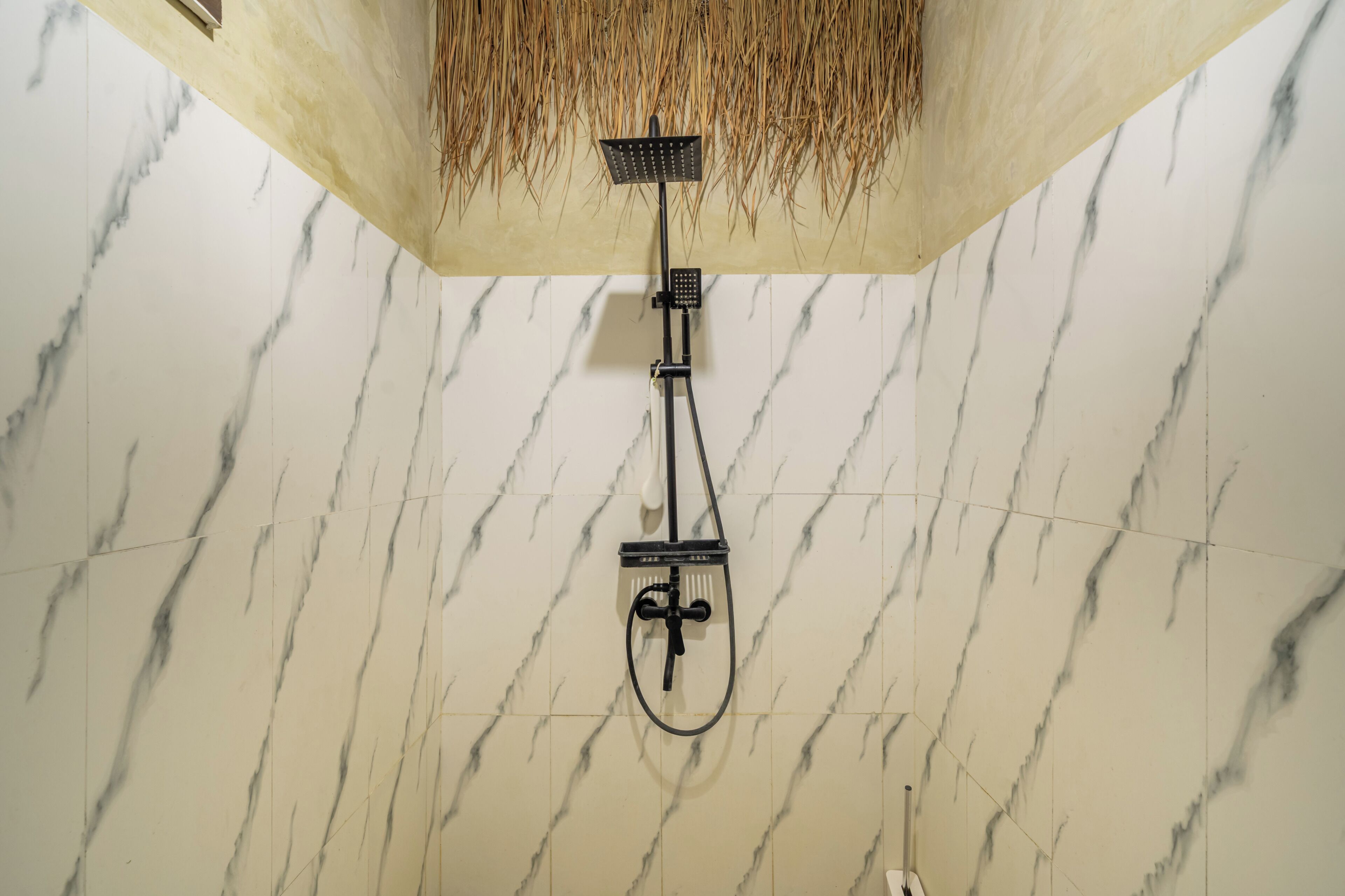 A shower with a handheld showerhead and a wall-mounted control panel.
