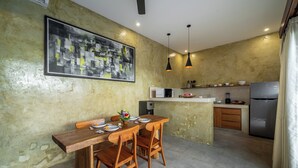 A modern kitchen with a dining area, featuring a large abstract painting, pendant lighting, and contemporary appliances. - Sona Villa Bali (Badung)