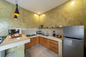 Una cocina moderna con un refrigerador de acero inoxidable, un microondas, una estufa y armarios de madera.