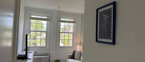 A room with a white sofa, a small white table, and two windows with white frames.