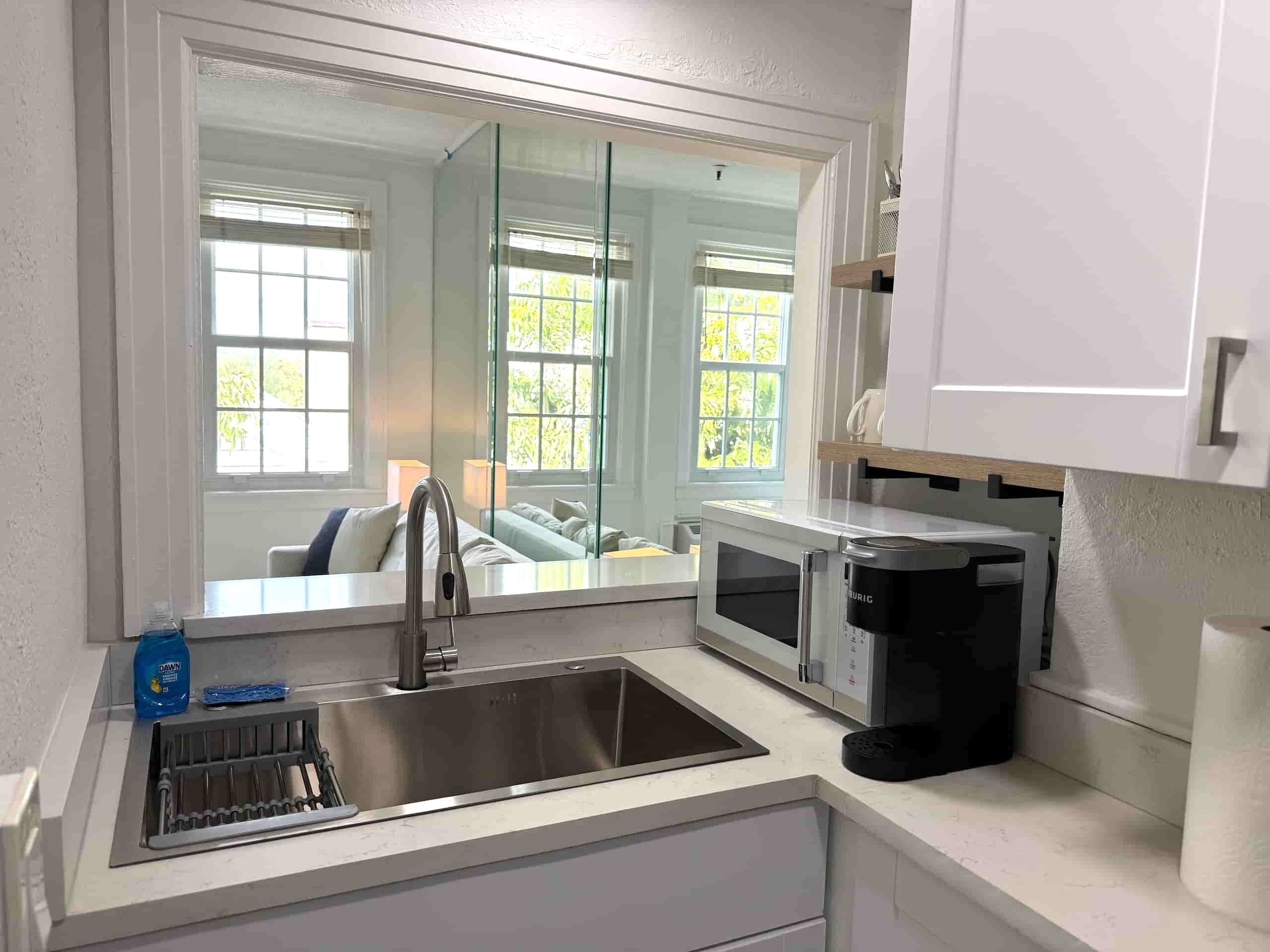 A modern kitchen with a stainless steel sink, a coffee maker, and a microwave.