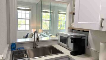 A modern kitchen with a stainless steel sink, a coffee maker, and a microwave.