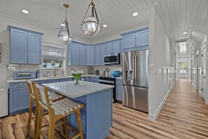 Eine moderne Küche mit blauen Schränken, Edelstahlgeräten und einem Essbereich aus Holz.