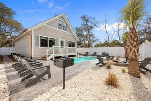 A house with a swimming pool, outdoor seating, and a palm tree. - Holy Crab!: 4BR 4BA, Pool, Fire Pit, EV Charger, Close to Beach, Sleeps 14 (Oak Island)
