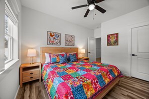 Ein Schlafzimmer mit einem hölzernen Bett, zwei Nachttischen mit Lampen, einem Deckenventilator und Bildern an den Wänden.