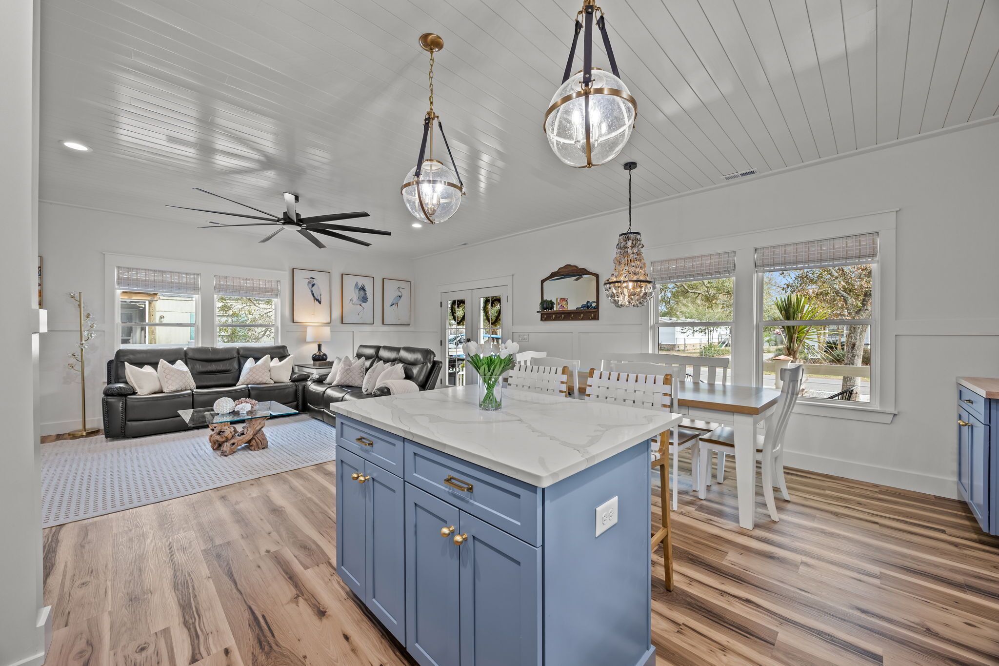 A spacious kitchen with a large island, wooden flooring, and pendant lighting.