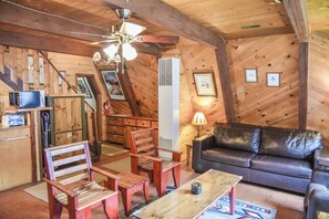 A cozy room with a wooden ceiling, a sofa, a coffee table, and a fireplace.