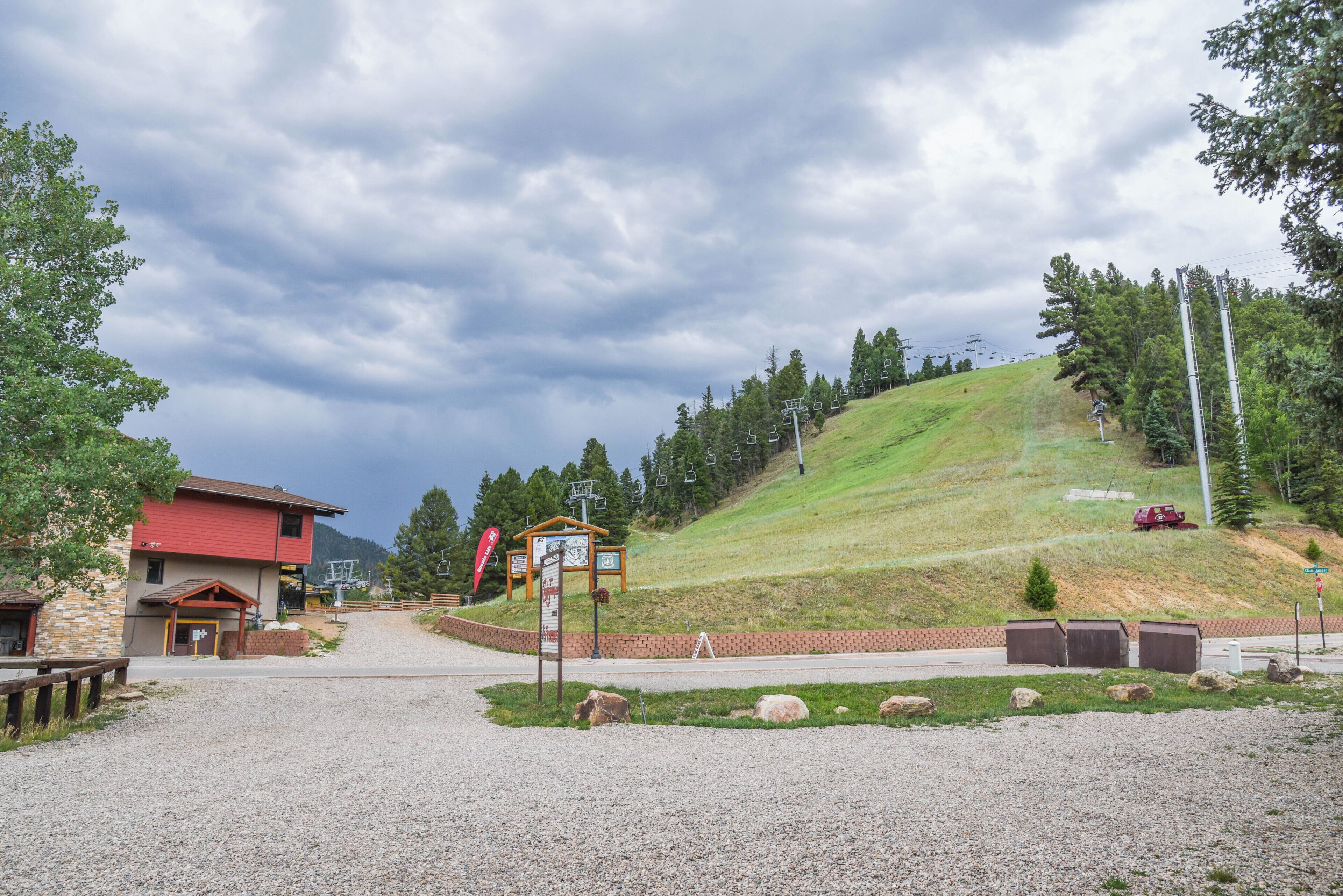 A ski resort entrance with a red building, a gravel path, and a signpost.