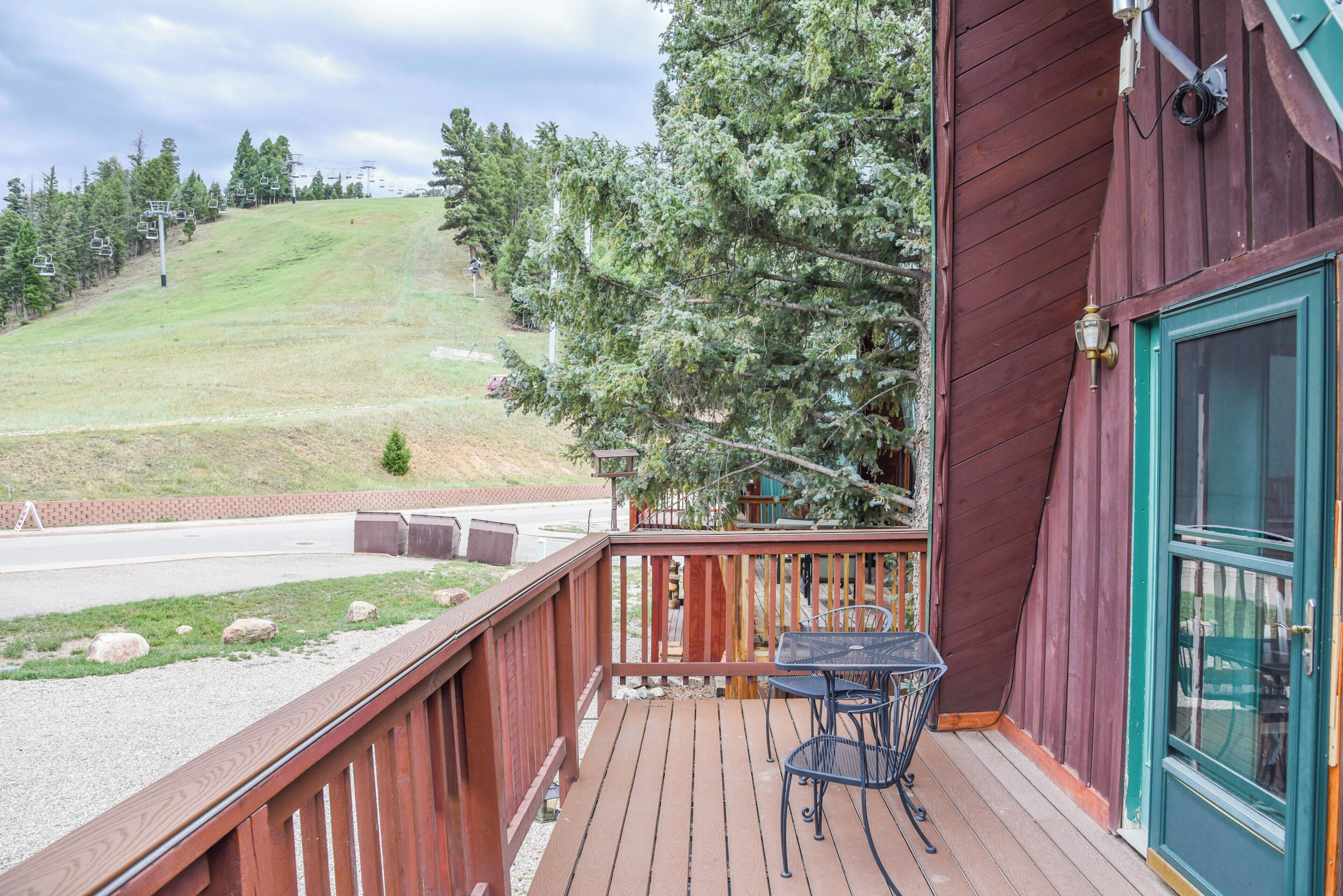 A wooden deck with outdoor seating, overlooking a ski slope with chairlifts.