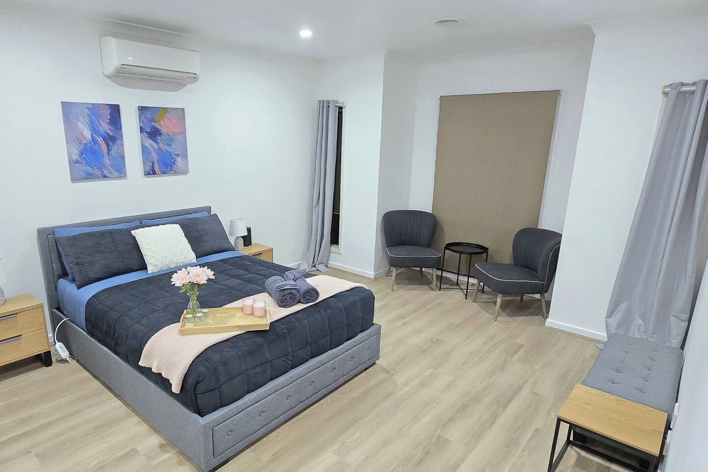 A modern bedroom with a bed, bedside tables, a chair, and a small table.