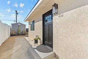 A house with a black door, a small porch with a doormat, and a cactus plant.
