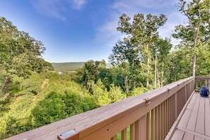 A wooden deck overlooking a forested valley with a clear sky.