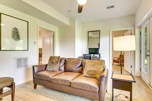 A modern living room with a leather sofa, a flat-screen TV, and a lamp.