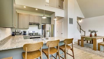 A spacious kitchen with a large island, stainless steel appliances, and a dining area with wooden chairs and a table.