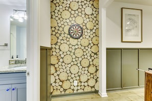 Un baño con una pared cubierta de rodajas de madera circulares, un dardo y un dibujo de patente enmarcado.