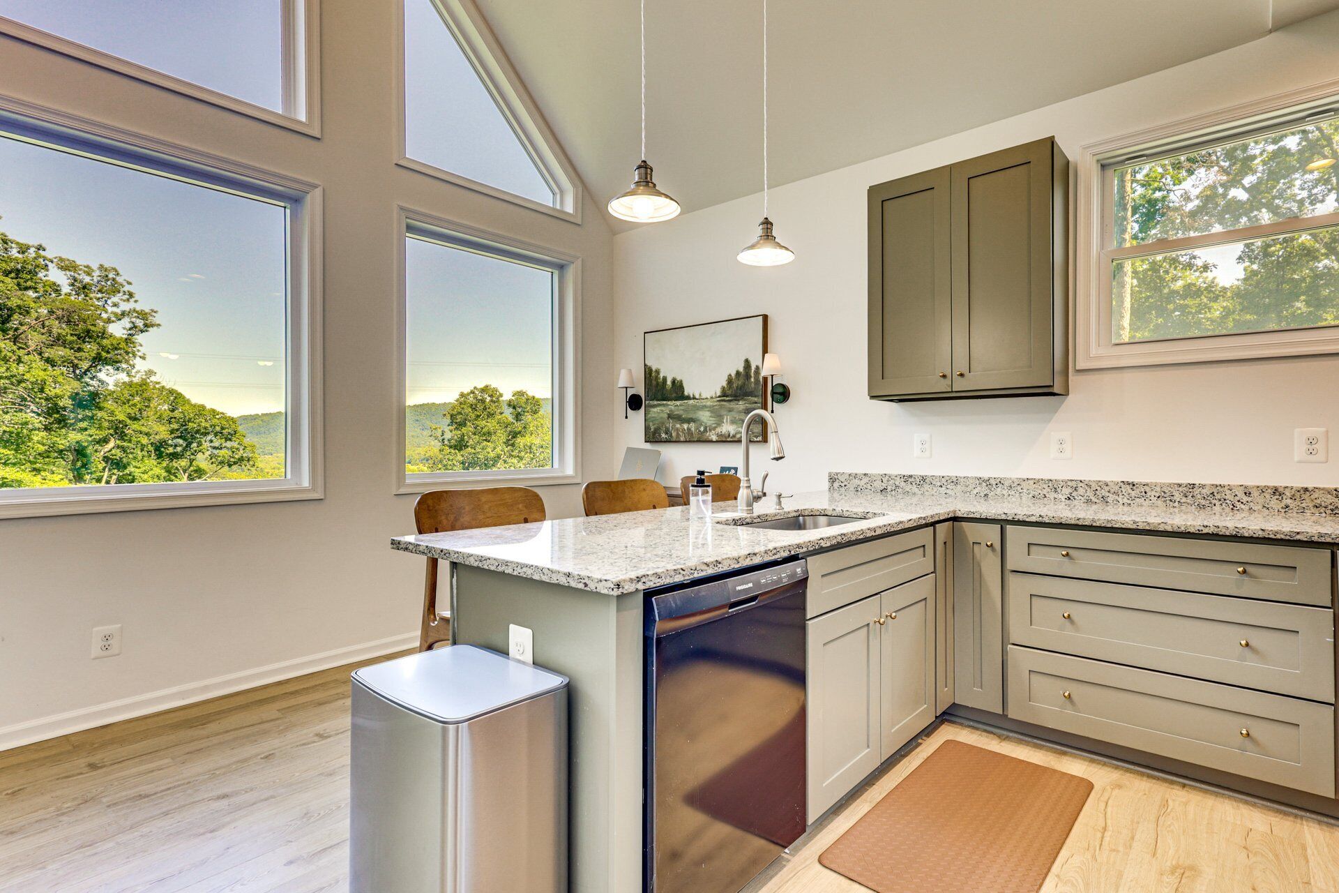 A modern kitchen with large windows, granite countertops, and stainless steel appliances.