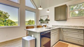 A modern kitchen with large windows, granite countertops, and stainless steel appliances.