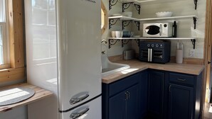 Una cocina compacta con un refrigerador blanco, un microondas, un tostador y un lavamanos.