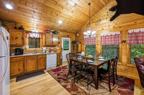 Ein Holzblockhaus-Innenraum mit Küche, Essbereich und einem Haustierhund.