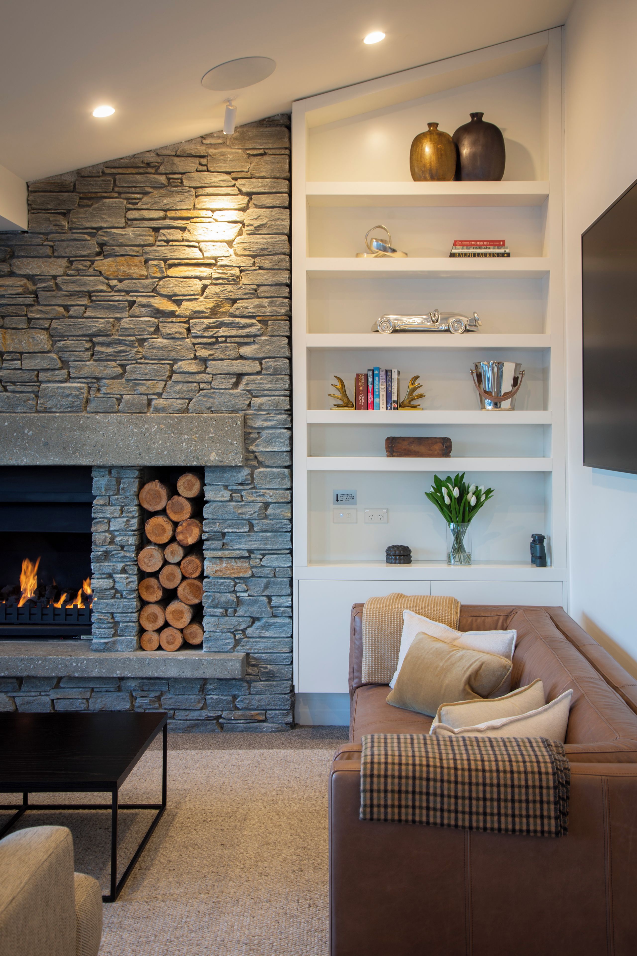A living room with a stone fireplace, a bookshelf, a sofa, and a coffee table.