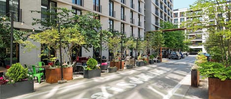 A modern urban street with a row of planters and outdoor seating along the sidewalk.