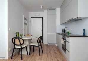 Eine kompakte Küche mit Essbereich, inklusive Kühlschrank, Herd und einem kleinen Tisch mit Stühlen.